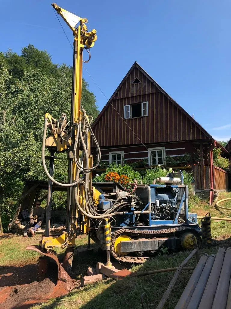 Pásová vrtná souprava s obsluhou vrtá studnu u horské chalupy