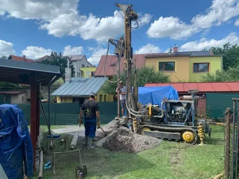 Pásová vrtná souprava vrtá studnu v malé městské zahradě