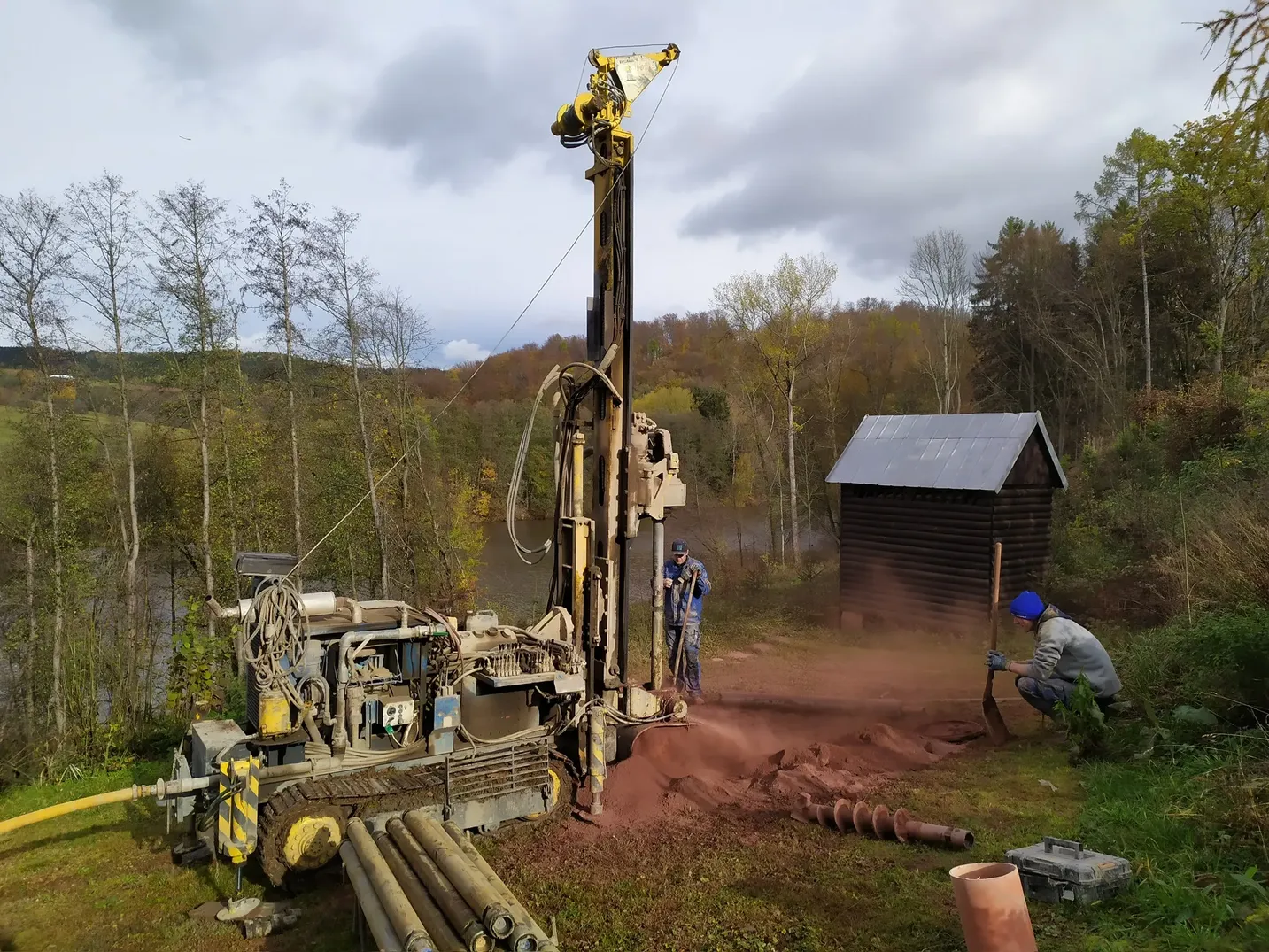Pásová vrtná souprava vrtá studnu nad rybníkem na podzim